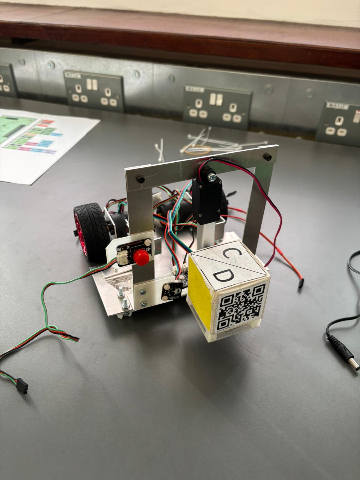 Miniature delivery AGV carrying a QR-coded payload during testing